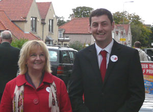 Cammy Day in a dark suit on Wardie Rd with a female constituent dressed in red