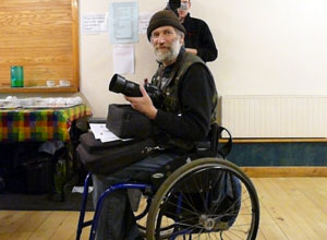 Bearded man sitting in a wheelchair holding a high quality camera