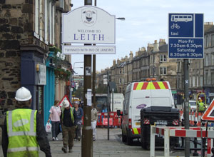 Workmen passing by the "Welcome to Leith: Twinned with Rio Janeiro" sign 