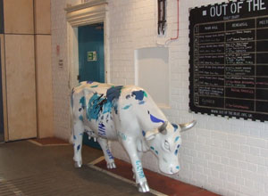 Pilmeny Youth Centre's  fibre glass cow (painted with names, blue on white) in its new home in The Old Drill Hall
