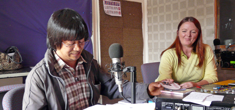 Kishor Dangol reads announces a Nepalese music track, as LEITH FM producer Fin Wycherley watches