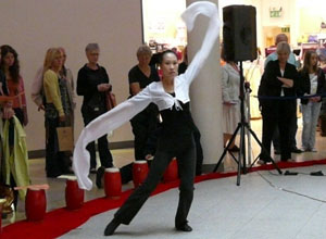 Woman in white sleeves over black pants dances with her arms extended