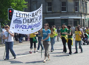 Marchers in the green and yellow of the Brazilain flag with a white banner