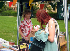 Woman eating a Renroc burger browses through LPs as a Friend of Montgomery St wearing a a white blouse with red roses watches on