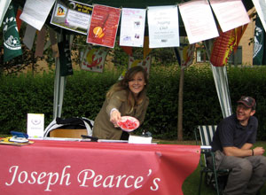 Woman member of the Pearce's team smiles offering strawberries under a gazebo