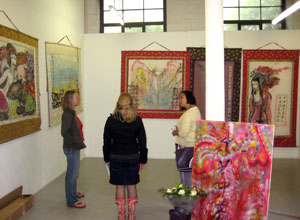 Three women chat, surrounded by painted silk hangings portraying Chinese women