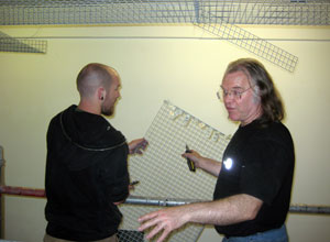 One man holding wire mesh, one man holding pliers