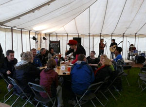 Large group seated round a table with the band, Sabai, on stage in the background