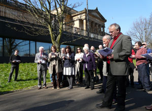 View of fifteen men and women singing from their programmes