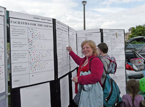 Joan putting up her stickers on the display boards to vote for her local priorites