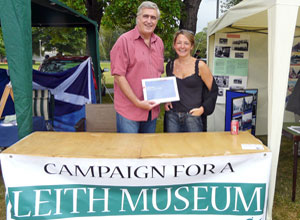A man and a woman hold up the  brochure outlining plans for  a Leith Museum