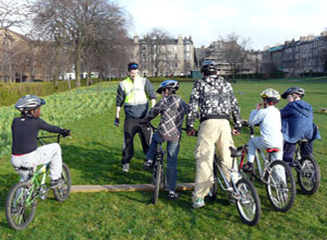 Four boys on bikes lined up with Remi of the Bilke Shop, with Elgin Terrace in the distance