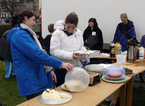 Two women laughing as they put cakes out on the stall