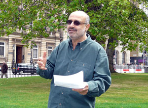 Iyad Hayatleh in dark glasses gesturing as he reads