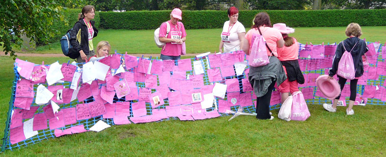 Women peg the notes that were on their backs as they ran to a memorial fence
