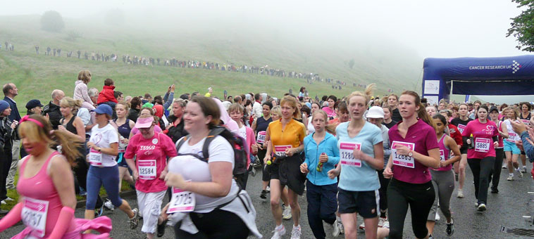 Dozens of women starting the Race For Life 2009 with watchers (in the background) looking down from  misty Salisbury Crags