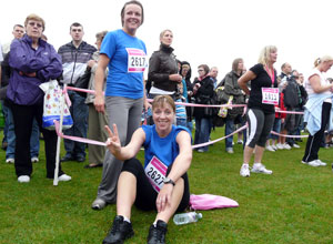 Two women in blue tee shirts, one standing one seated