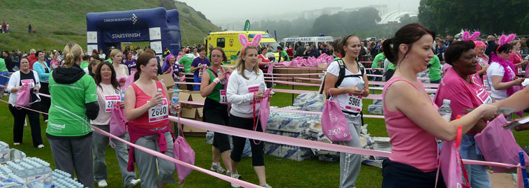 Women in pink walking up the pink ribboned lanes collecting  congratulations, bottles of water and  pink Tesco gift bags