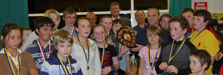 Hibs Legend Mickey Weir holds up the Show Racism the Red Card shield, surrounded by children and young people