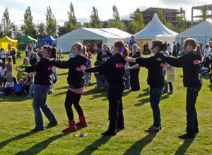 Five young people sequence dancing with their hands on each others shoulders