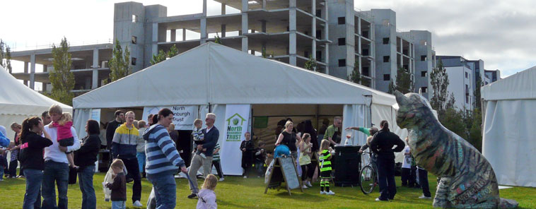 View of North Edinburgh Trust marquees with flats in construction in the background and a papier mache cat in the foreground