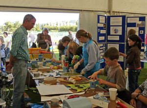 Children and adults gathered round tables, making and painting masks