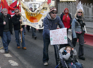 Young couple with buggy and small child, and the poster "TRIDENT...YOU MUST BE TALKING OUT OF YOUR NUCLEAR ARSENAL
