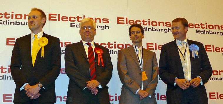 Candidates Kevin Lang (Lib Dem), David Jacobsen (Socialist Labour), and Iain McGill (Conservative), with Mark Lazarowicz as the results are announced