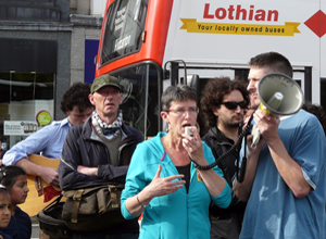 Woman in sapphire  jogging top speaking through loud hailer