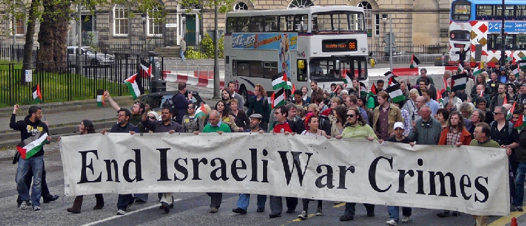 "End Israeli War Crimes" banner being organised with buses behind, with marchers coming into Charlotte Square