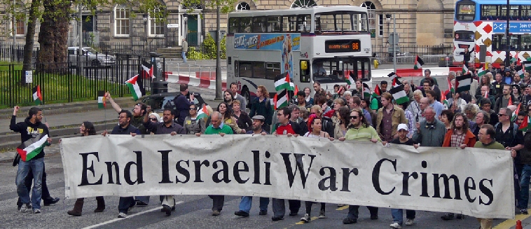 "End Israeli War Crimes" banner being organised  with buses behind,  with marchers  coming into Charlotte Square