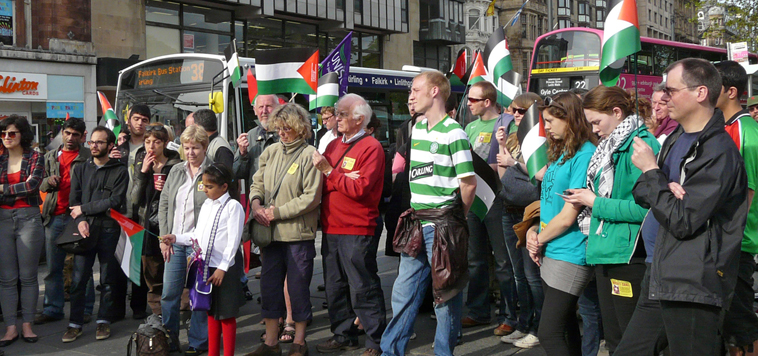 People of all ages listening to speeches as buses go along Princes St