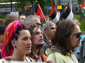 A young woman with pink and orange dreadlocks and two longhaired men