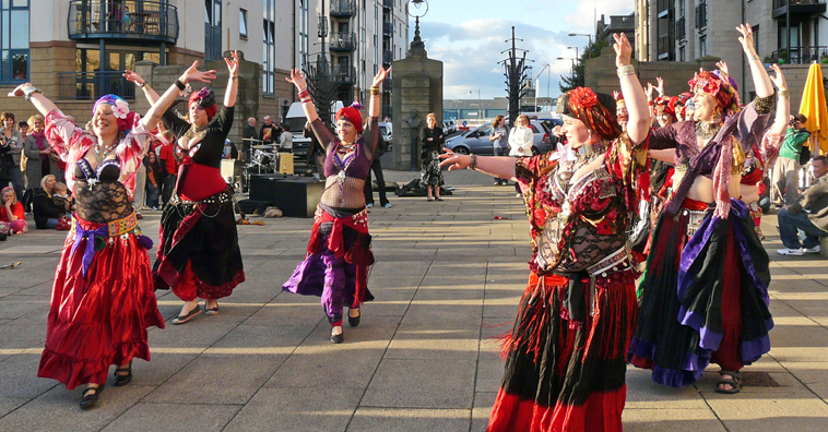 Twisted Tails Belly Dance troupe dance outside  The Malmaison by The Shore, wearing red and purple outfits