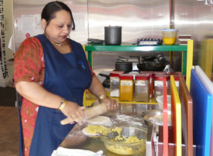 Woman in a blue apron rolling out  a bread mix