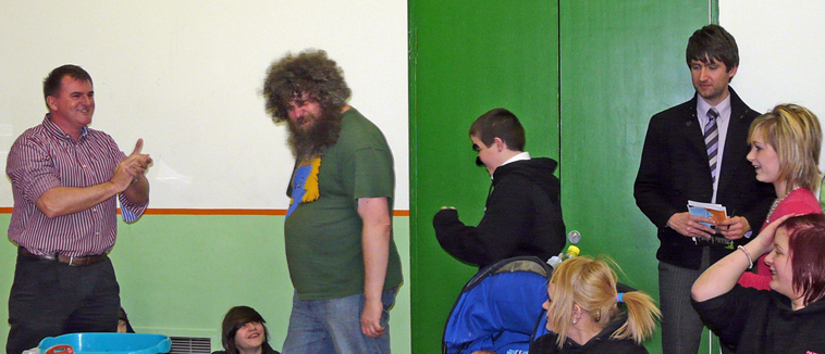 Willer Barr applauds as Dave walks in wearing a green tee shirt and an Evening News corresopndent, young people, and Finlay Smith watch on