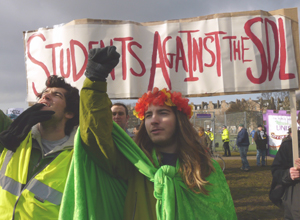 Young man with a wreath of orange and  yellow carnations round his long hair, raising his arm in salute