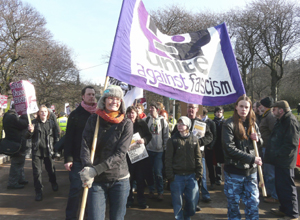 The Unite Against Fascism banner  in  purple and black on a white background
