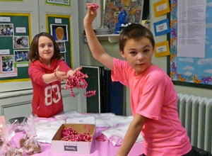 Girl with pink bracelets running through her fingers and boy waving pink bracelet