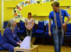 Man in scarf and blue teashirt walks past Penny, sharing a smile