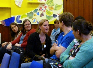 Woman in black cardigan talks urgently to seated people around her
