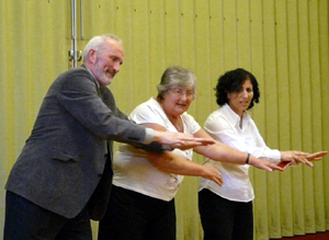 A man and a woman pusing outstretched arms with a perplexed looking woman