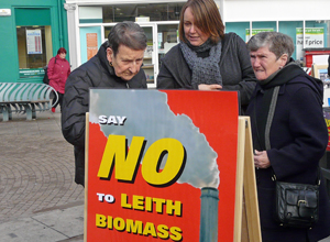 Three people look at an A Board saying "SAY NO TO LEITH BIOMASS