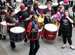 Two rows of cheerleaders in black trousers and red tops with pink pom poms