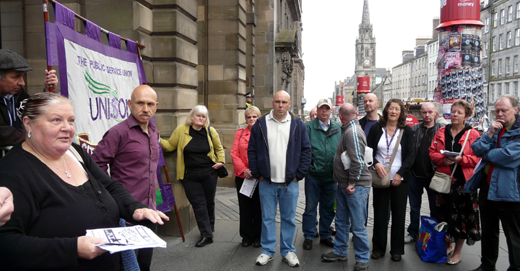 speaking to a group outside the City Chambers with a view of the High St in the background