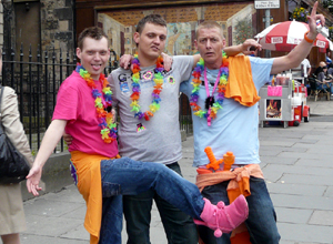 Three men with rainbow garlands posing raffishly