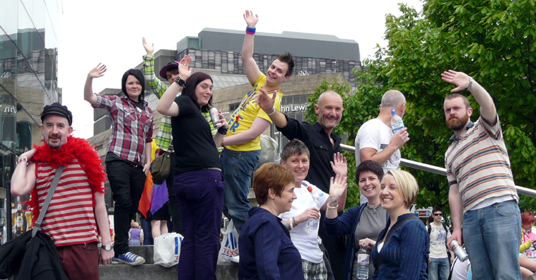 Groups of people waving, standing on the steps of the Omni Centre, with the St James Centre in the background