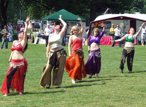 Cheerleaders in silver tops and black flared trousers in a circle doing a Mexican wave with their pom poms