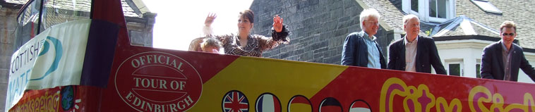 View of the red & yellow open top bus with a Scottish Water banner on the front, and Mark Lazarowicz MP and Malcolm Chisholm MSP, both representing Edinburgh North & Leith Constituency and Leith Cllr Rob Munn