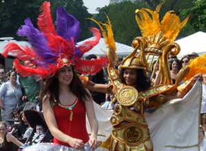 Two young women smiling and dancing in orange, scarlet and purple feathers.